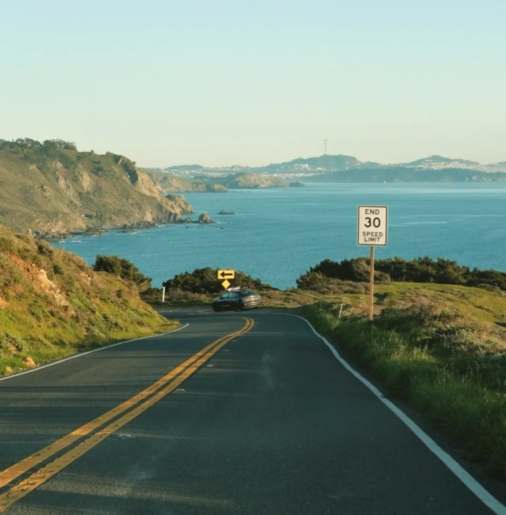 Scenic coastal highway with ocean views and speed limit sign showcasing beautiful solo road trip destination