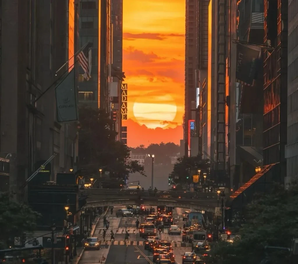 A breathtaking view of the Manhattanhenge sunset, where the setting sun aligns perfectly with the street grid of Manhattan, creating a golden glow between tall buildings.