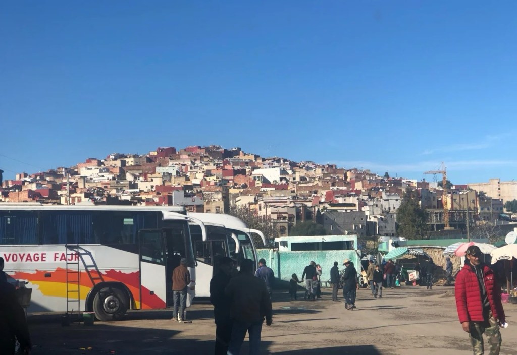 Busy Moroccan bus station and market area with crowds where tourists should be aware of common scams and overcharging