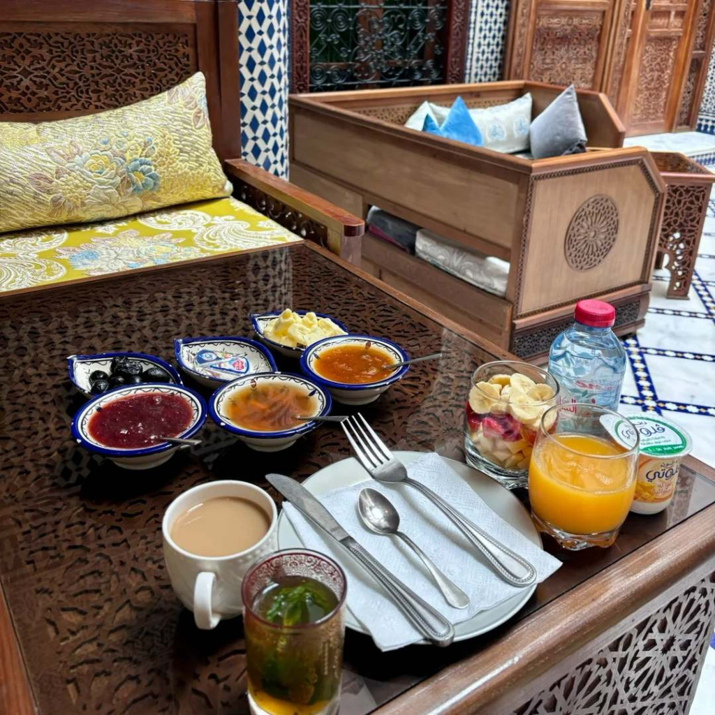Traditional Moroccan breakfast spread in riad with mint tea, local jams, bread, and authentic serving dishes