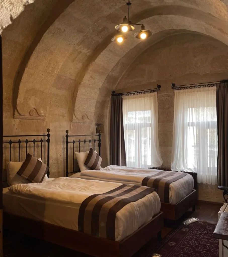 Authentic cave hotel accommodation featuring stone arched ceilings, twin beds, and traditional Turkish decor in Cappadocia