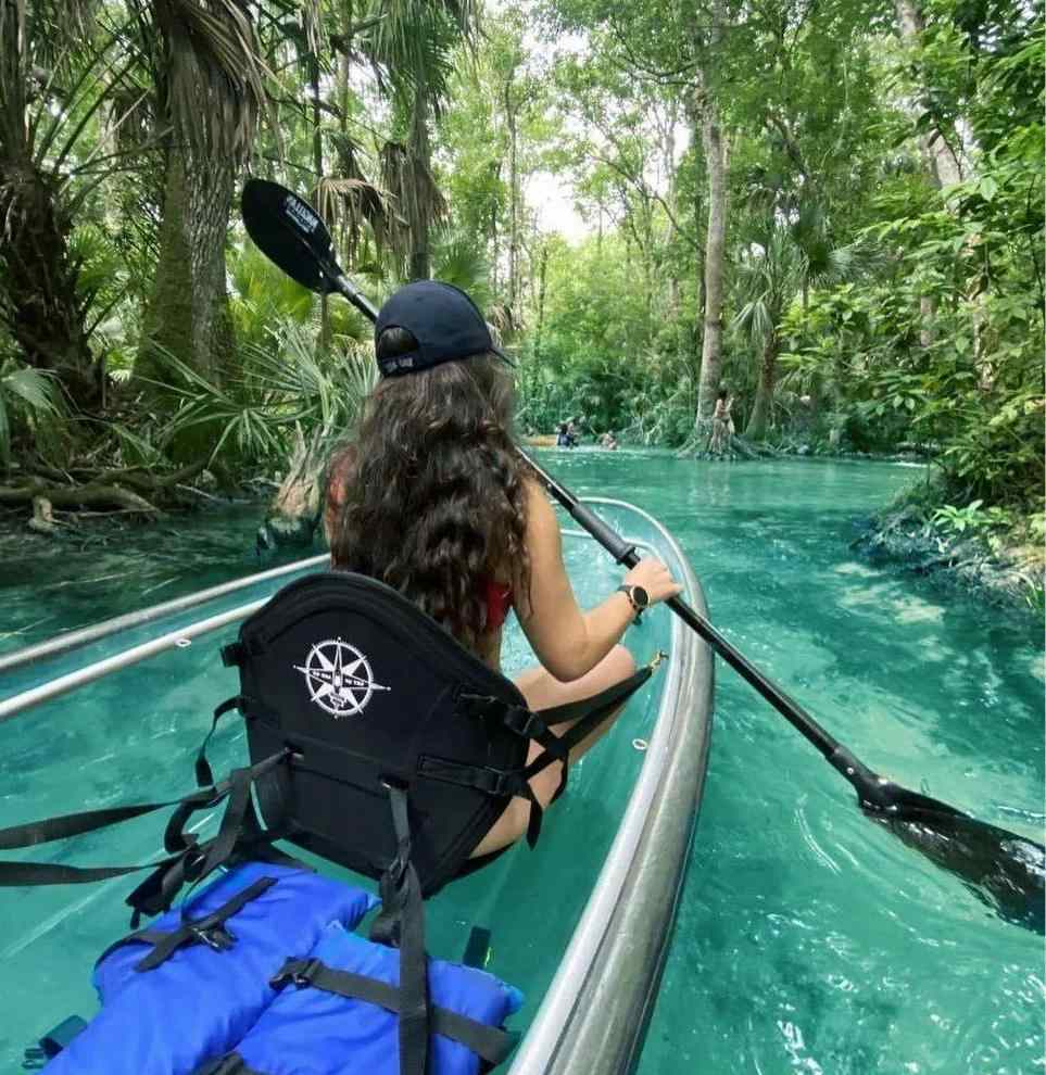 Woman solo kayaking, clear river, forest exploration.