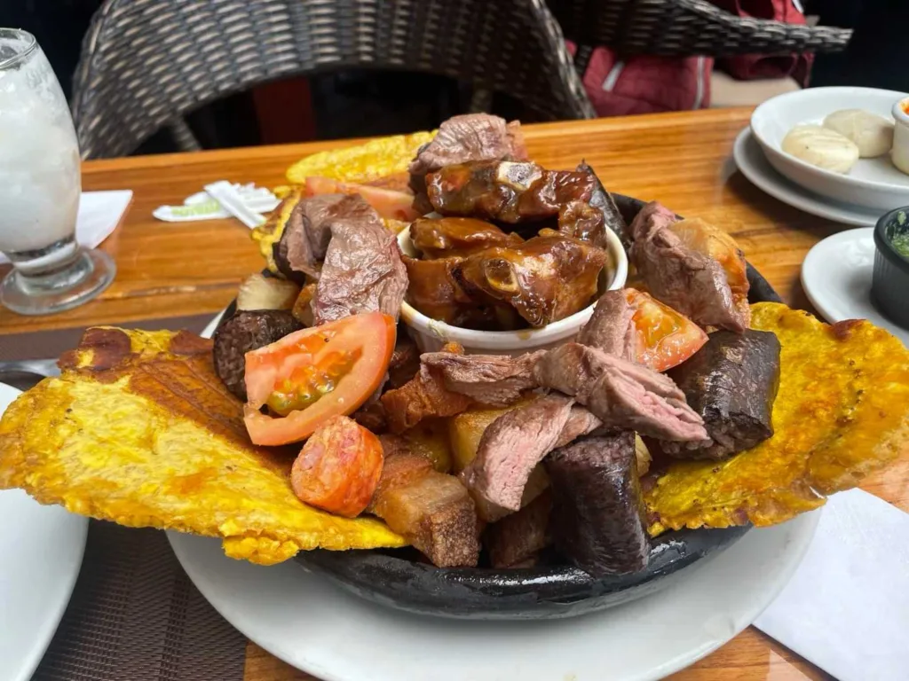 Large serving platter with sliced grilled beef, sautéed mushrooms, tomatoes served on golden fried plantain patacón base