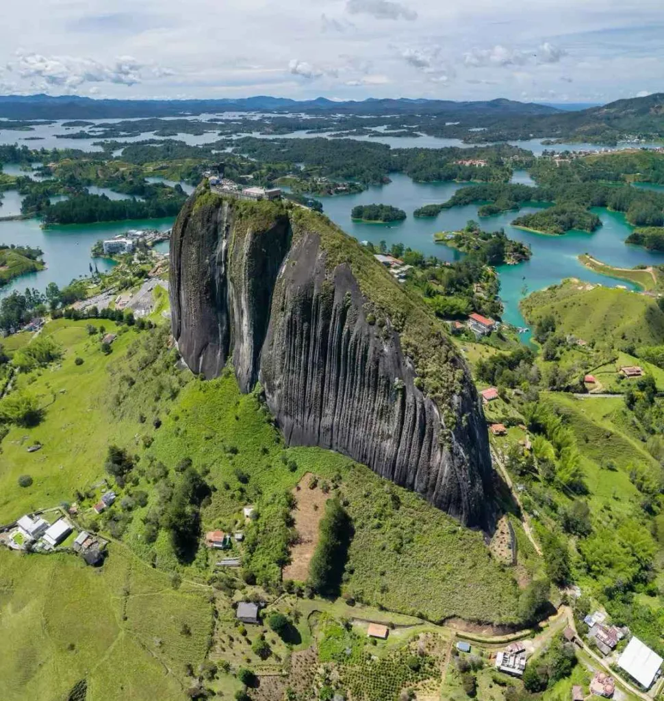 Dramatic aerial view of El Peñol Rock monolith rising above Guatapé reservoir with emerald islands in Colombia