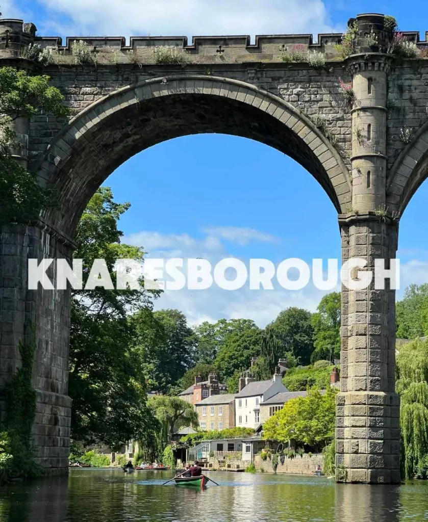 Historic stone railway viaduct in Knaresborough with boat on River Nidd and medieval architecture in Yorkshire