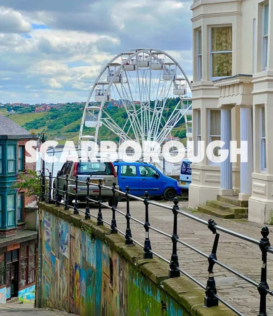 Large white ferris wheel on Scarborough seafront with Victorian terraced houses and coastal views in Yorkshire