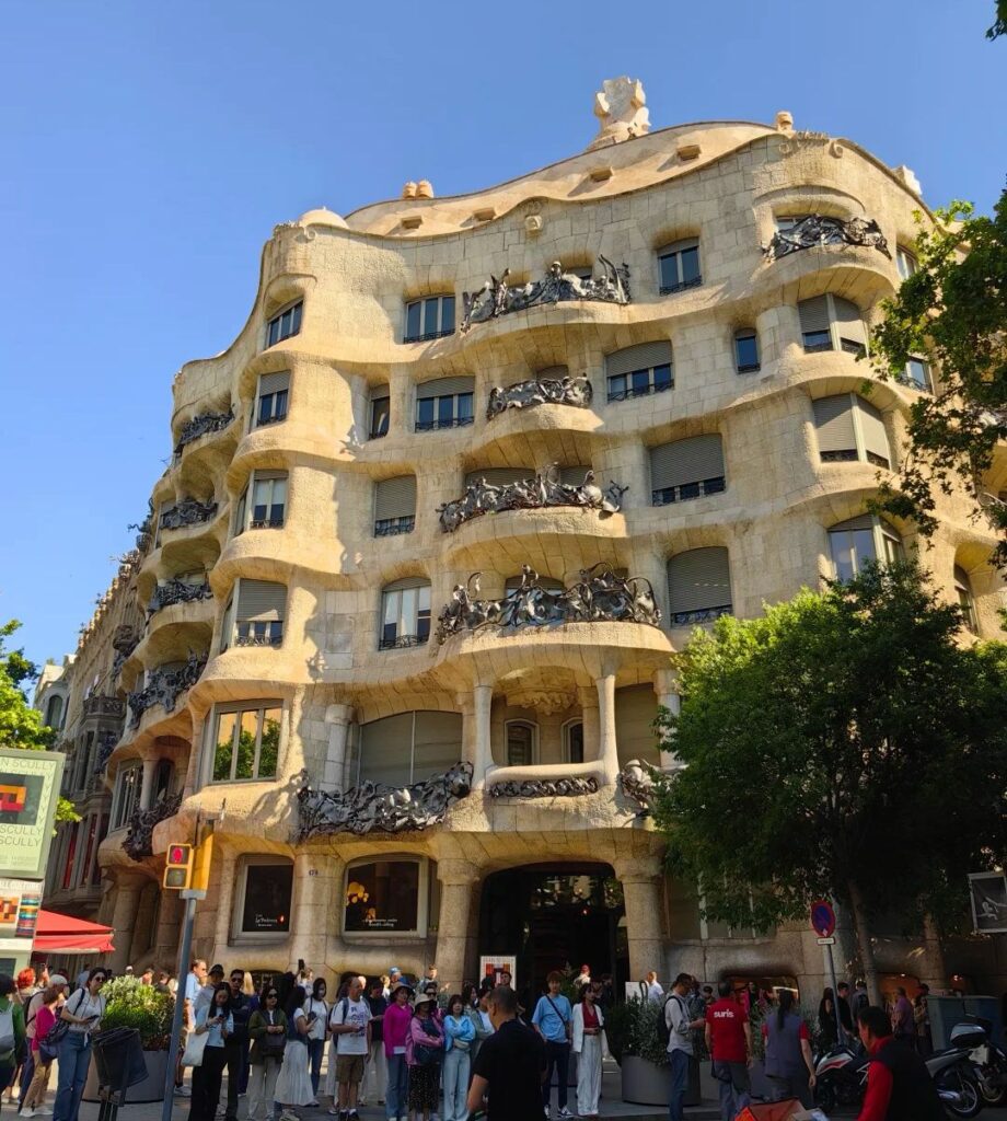 Famous Casa Milà La Pedrera building on Passeig de Gràcia with tourists visiting Barcelona's luxury shopping district