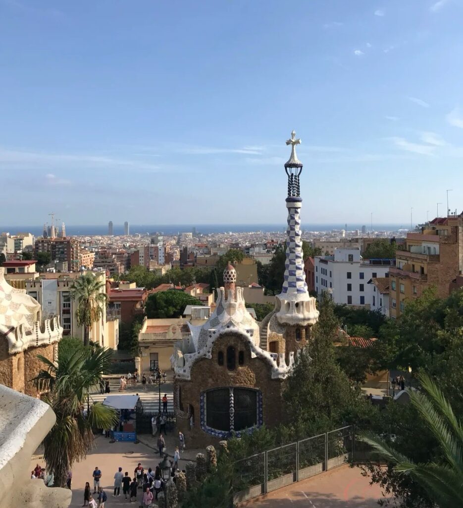 Park Güell featuring Gaudí's distinctive mosaic architecture with panoramic Barcelona cityscape and Mediterranean Sea in background