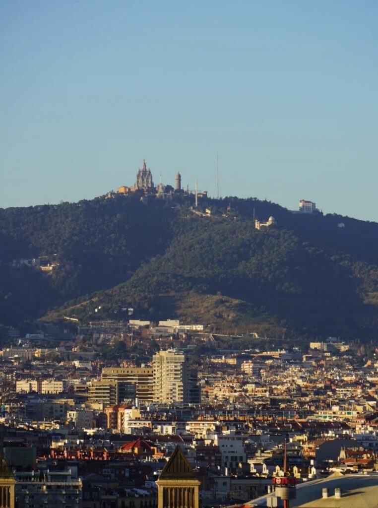 Panoramic view of Barcelona showing Tibidabo mountain with church and telecommunications tower overlooking the sprawling city