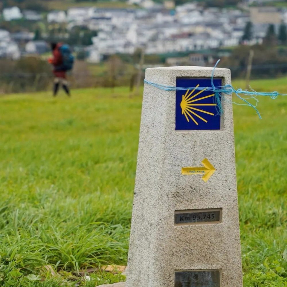First Camino guide waymarker showing km 95.745 with scallop shell symbol and yellow arrow for route navigation