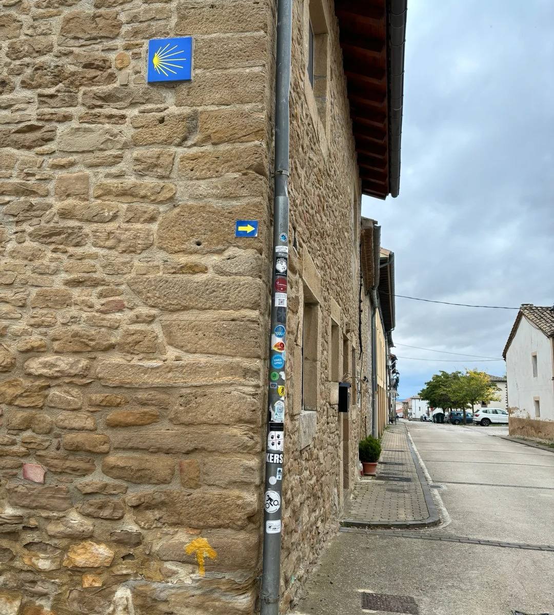 First Camino guide stamp collection spots showing various pilgrim stickers and Camino symbols on stone wall