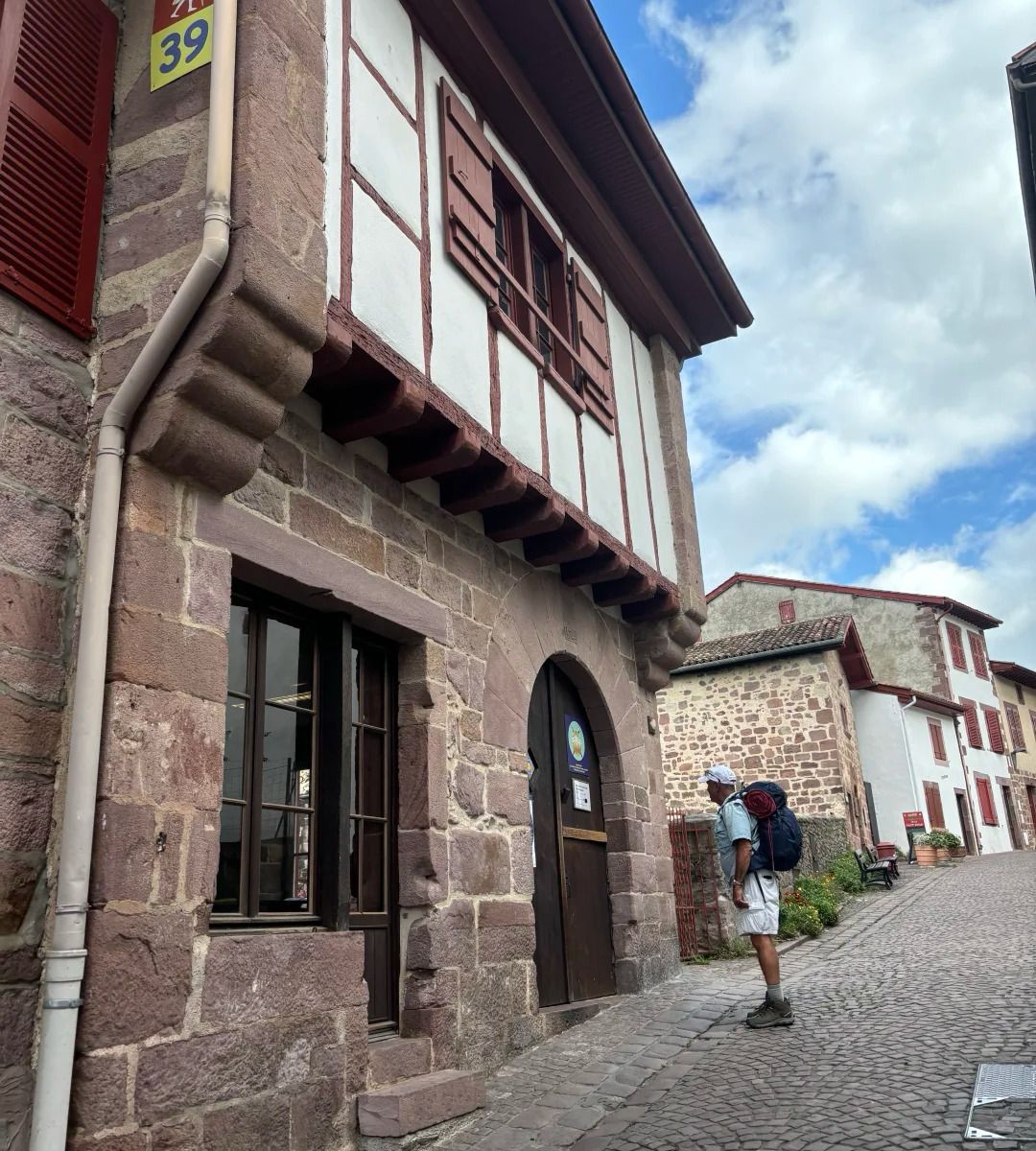 First Camino guide pilgrim visiting traditional stamp office in historic stone building along the route