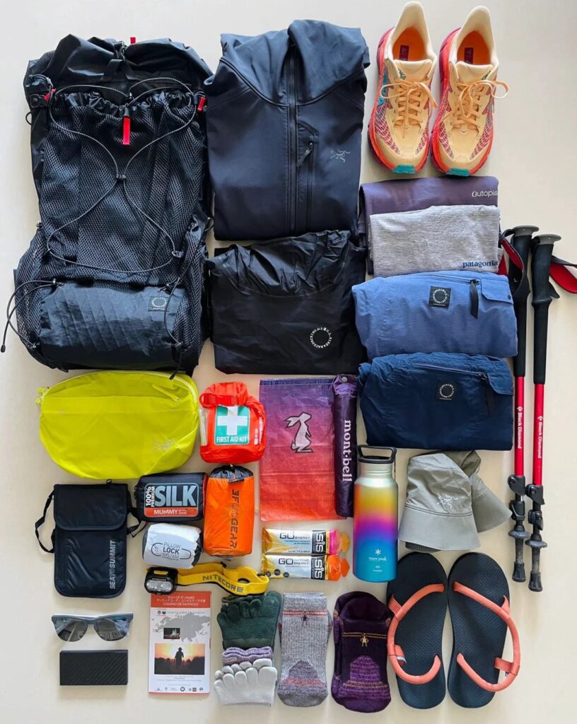Complete Santiago Ways packing gear layout showing backpack, hiking boots, clothing, and essential equipment