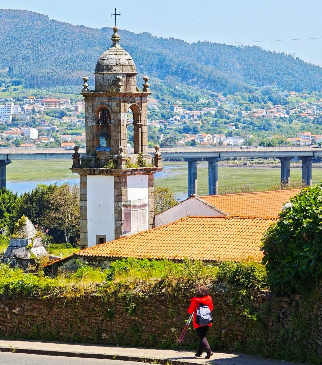 Santiago Ways pilgrim walking Portuguese route past historic church bell tower and countryside