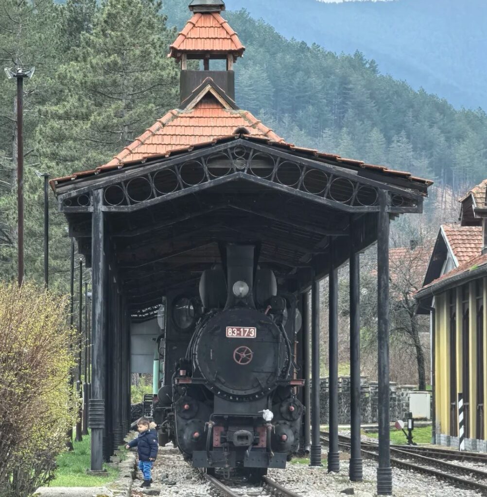 Vintage steam locomotive numbered 83-173 at wooden station platform on famous Šargan Eight narrow-gauge railway in Serbian mountains