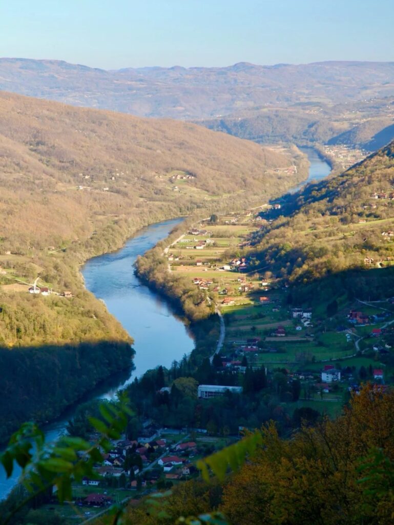 Spectacular panoramic view of Drina River winding through Tara National Park with forested mountains and rural villages in Serbian wilderness