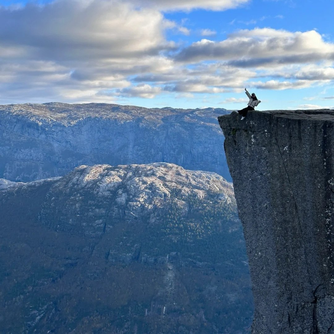 Norway road trip destination Preikestolen Pulpit Rock with hiker enjoying dramatic cliff views over Lysefjord