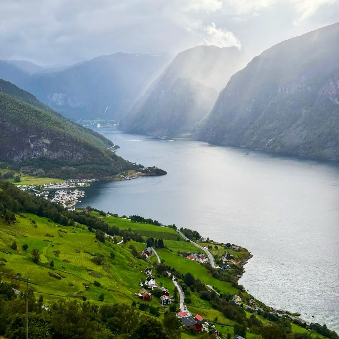 Norwegian fjords scenic panoramic view showing ancient valley with traditional village and dramatic mountains