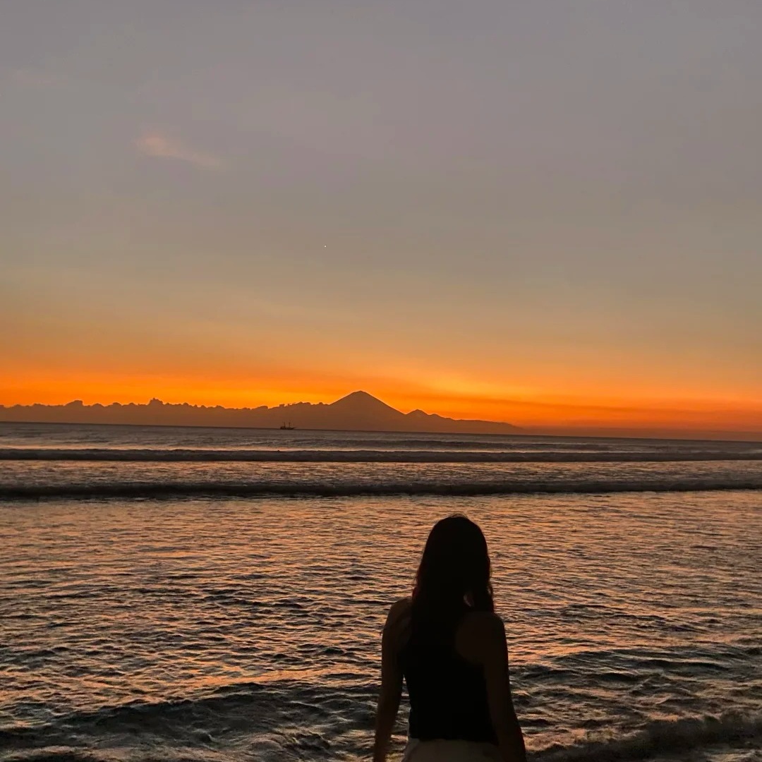 Solo female travelers beach sunset contemplation silhouette