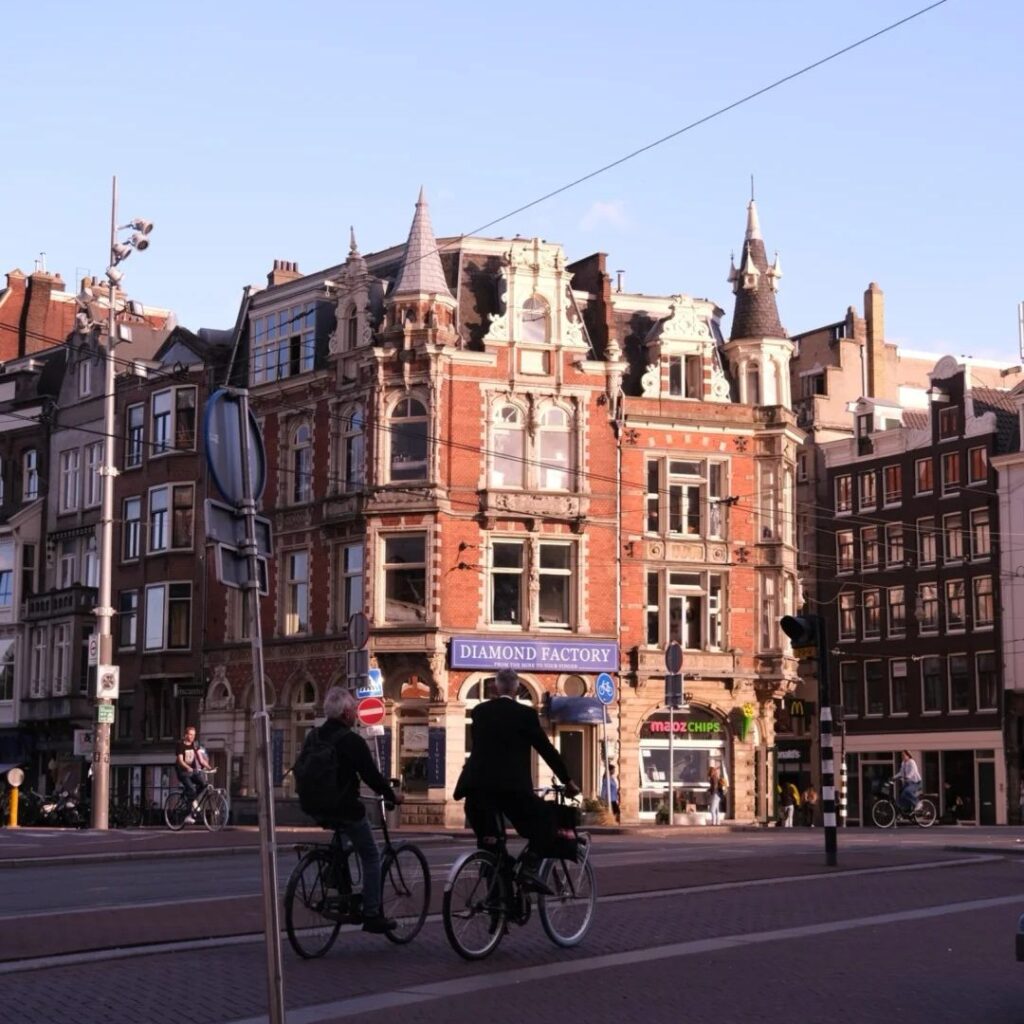 Places stay Amsterdam traditional corner building with cyclists and Diamond Factory shop