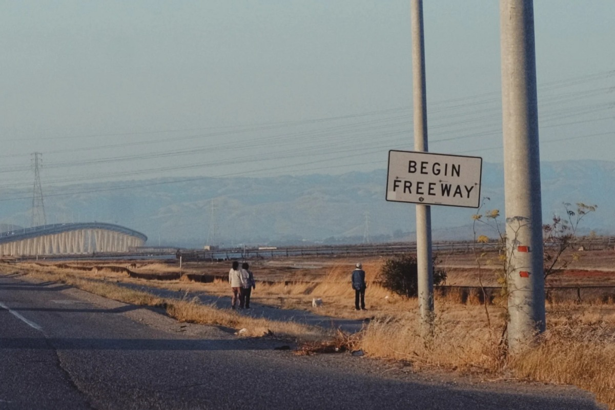 Highway begin freeway sign marking the start of solo road trip adventure with bridge in background