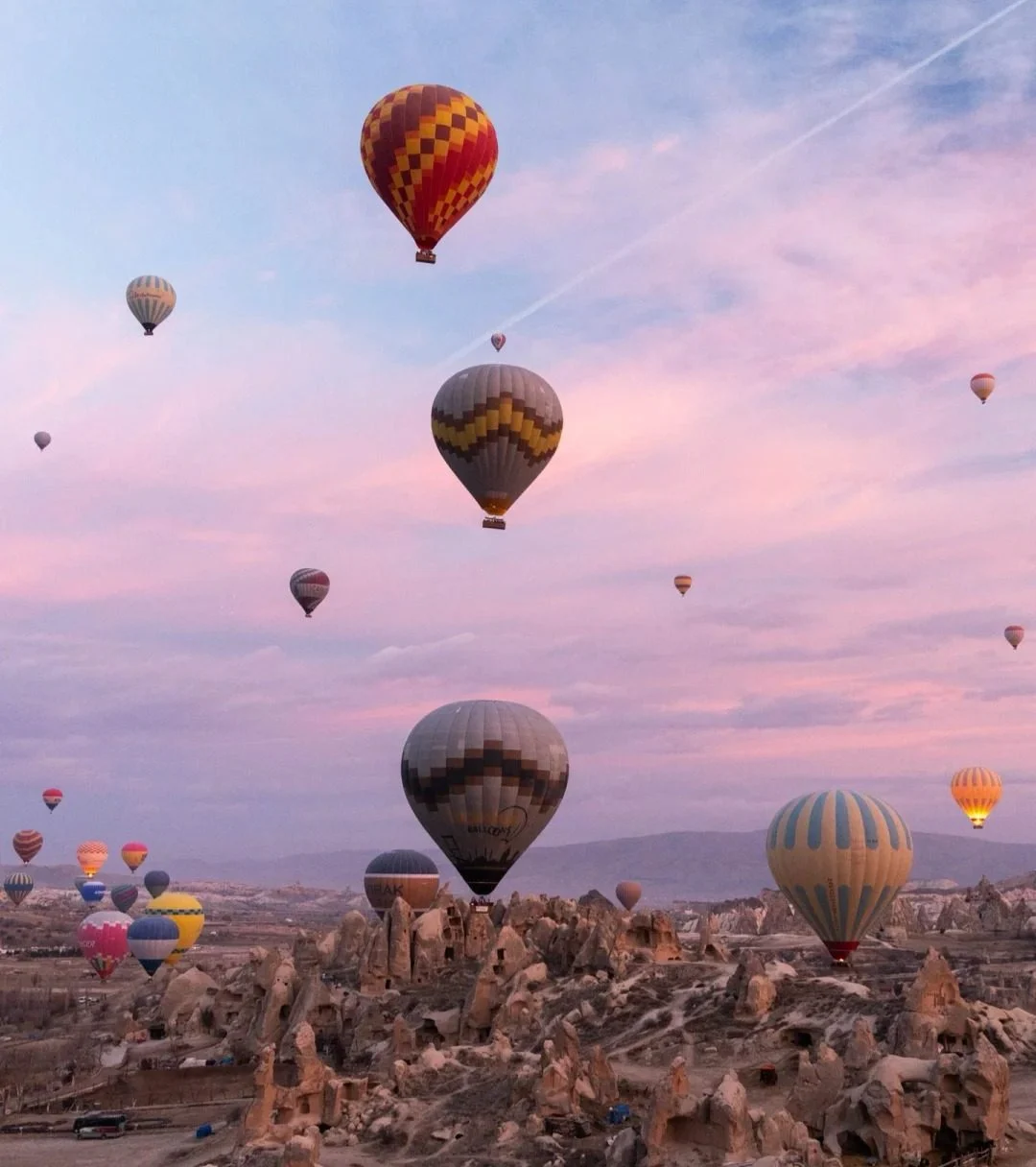 Spectacular sunrise view of colorful hot air balloons floating over Cappadocia's unique rock formations and fairy chimneys in Turkey