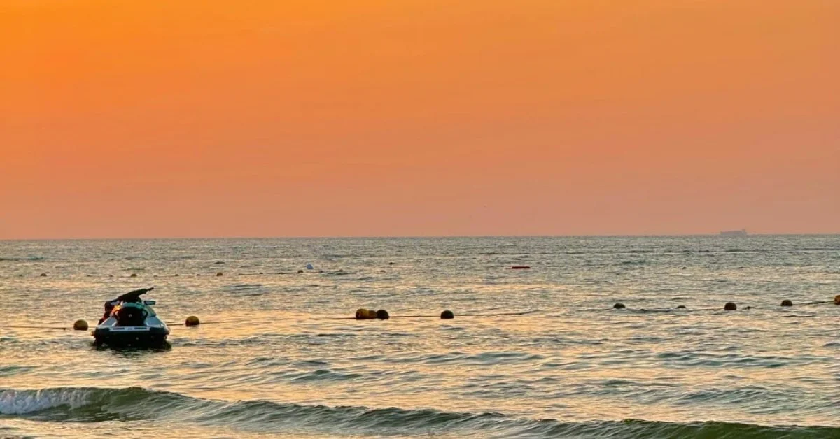 Jet ski floating on a calm ocean at sunset with a warm orange sky, hinting at tranquil travel moments.