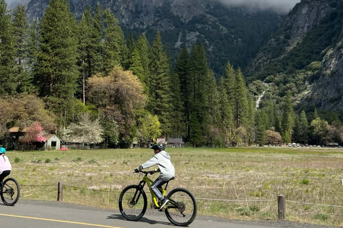 Cyclist wearing crossbody vest bag while mountain biking on scenic road with mountains in background