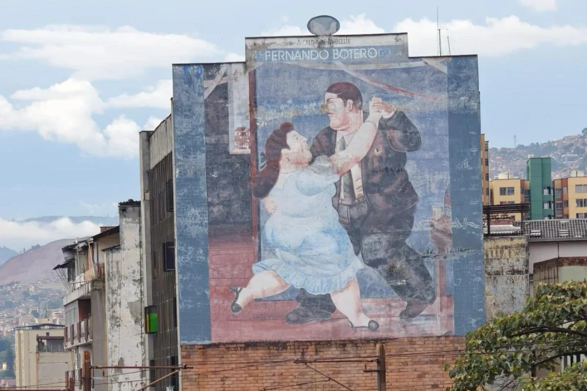 Large street mural featuring Fernando Botero's distinctive fat figure art style depicting dancing couple in Colombian city