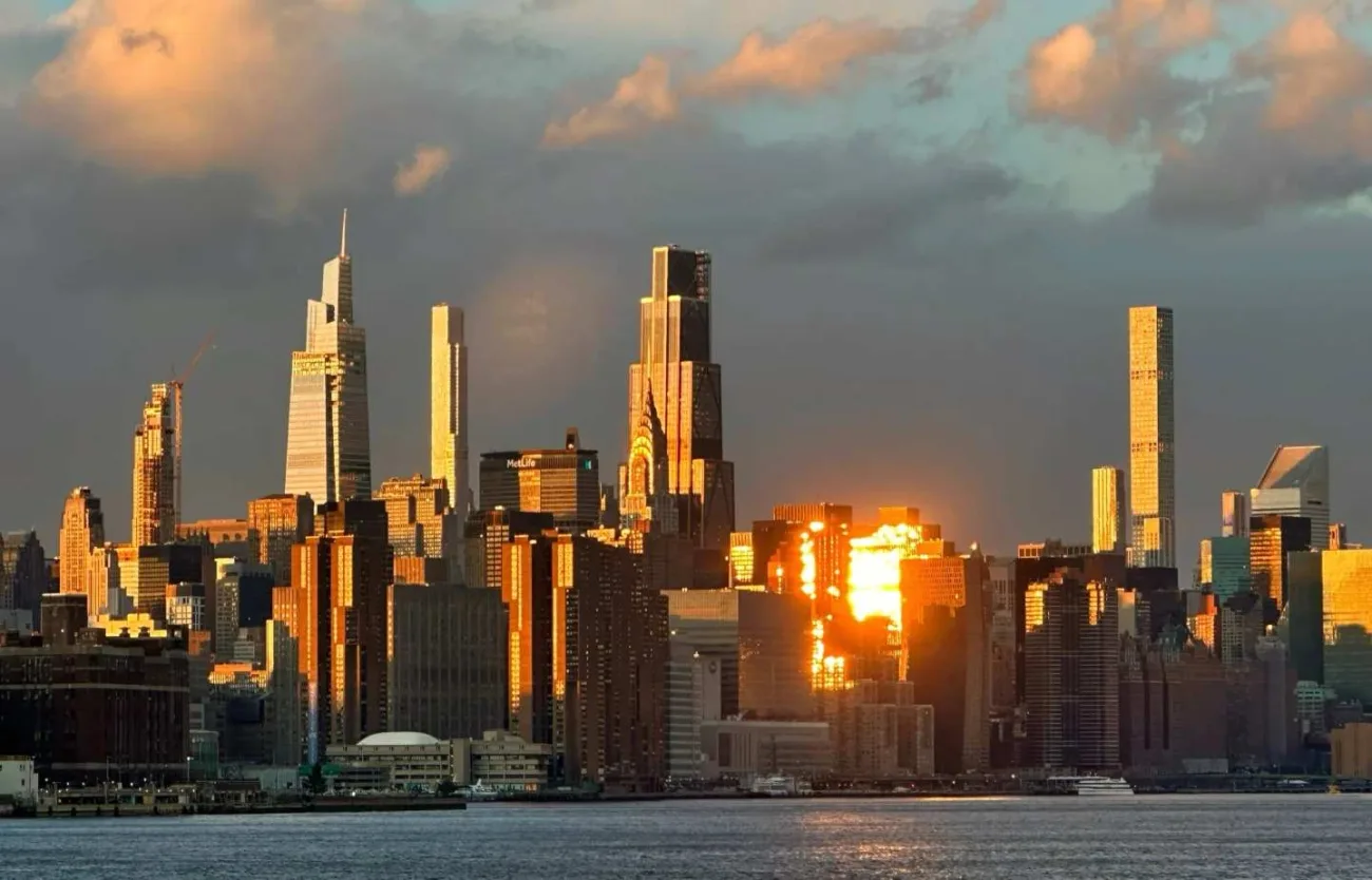 Stunning Manhattan skyline at golden hour sunset viewed from Brooklyn waterfront with dramatic clouds and lighting