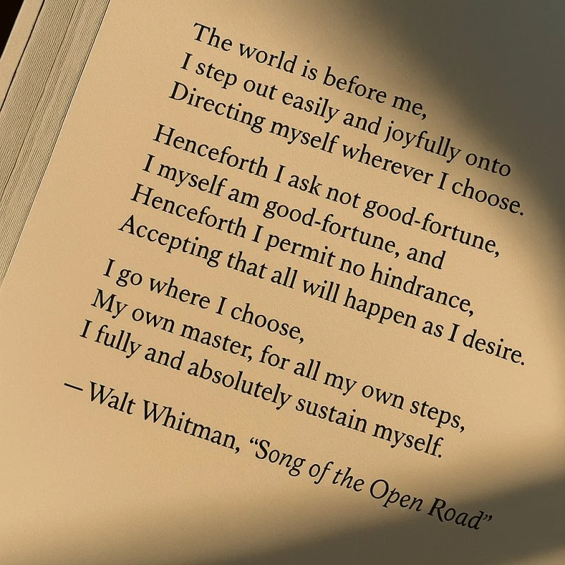 A close-up of a book page displaying an inspirational quote from Walt Whitman's "Song of the Open Road" about freedom and self-reliance.