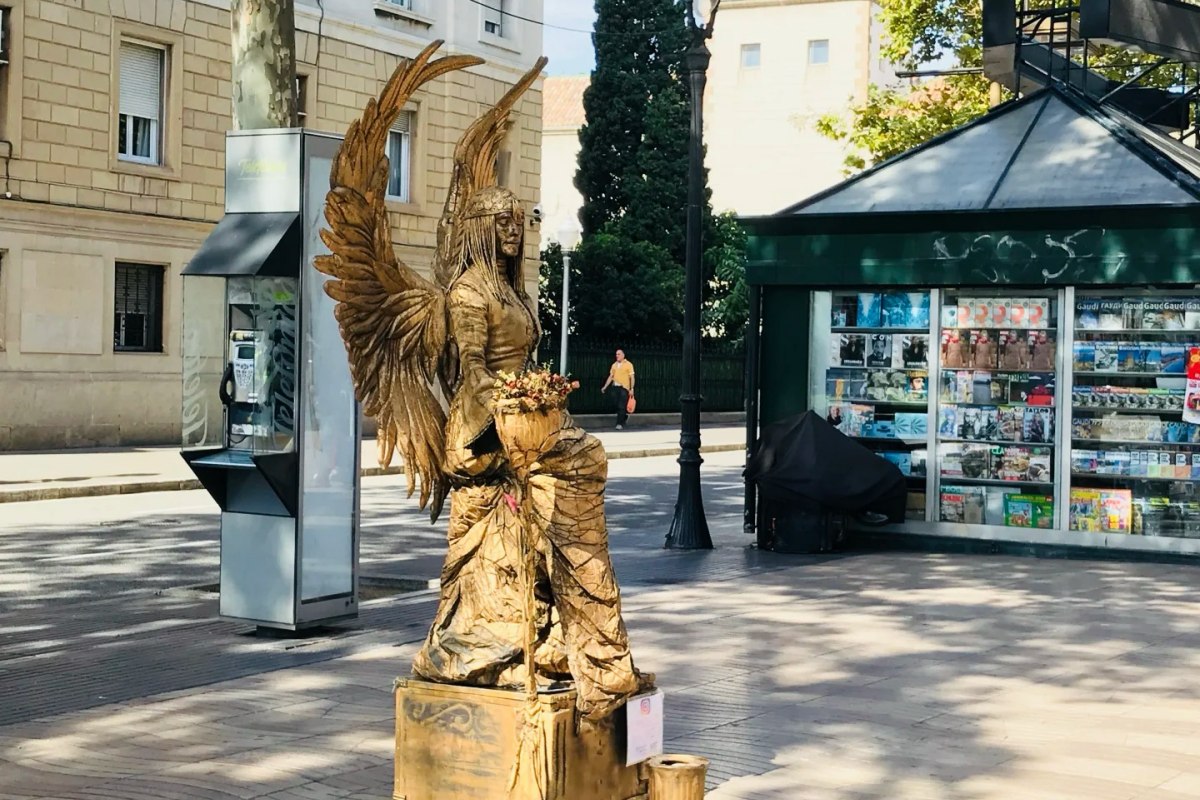 Golden painted street performer dressed as angel with wings performing on Barcelona's Las Ramblas pedestrian street