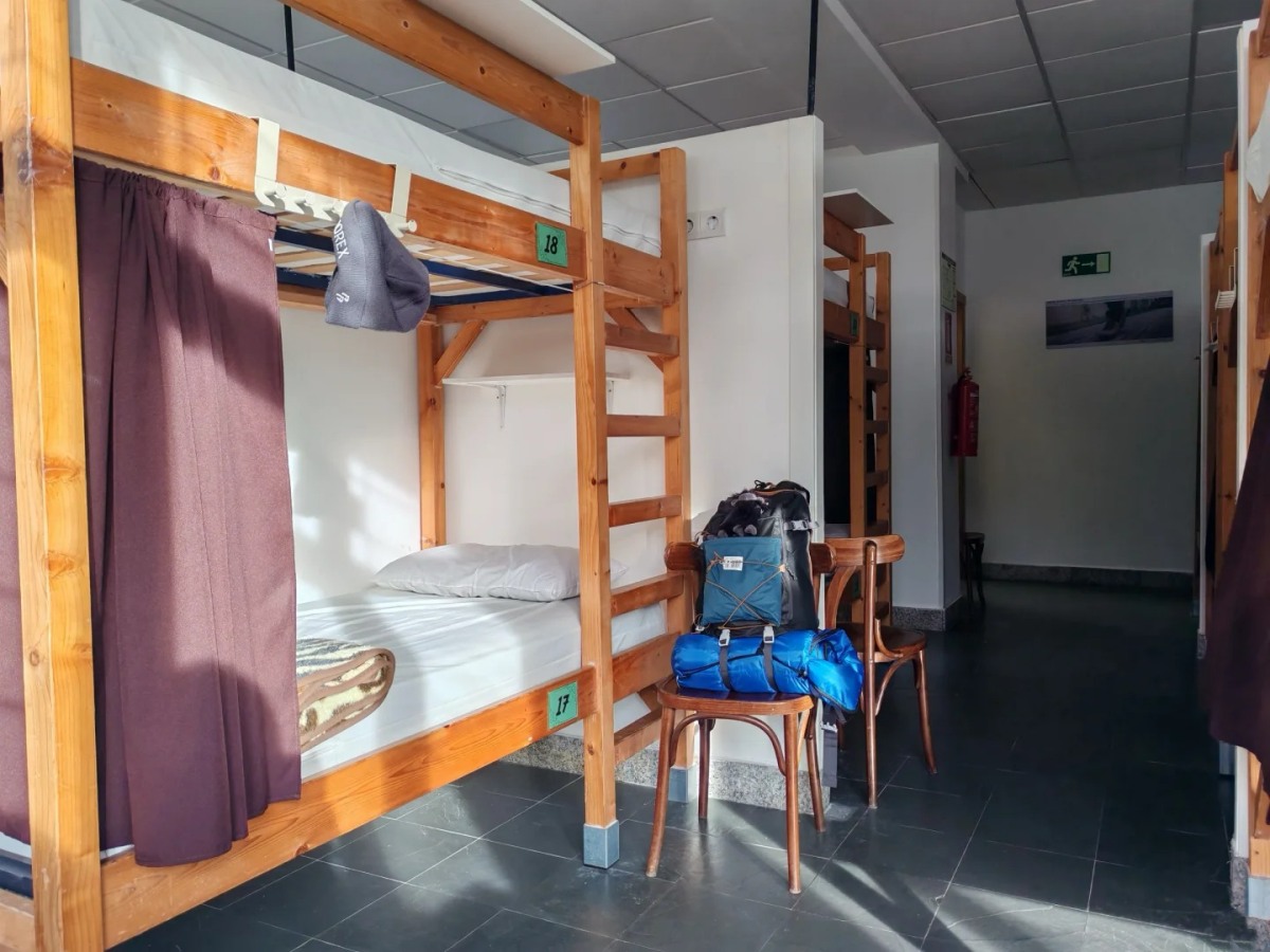 Modern albergue dormitory with bunk beds and pilgrim backpacks Santiago Ways