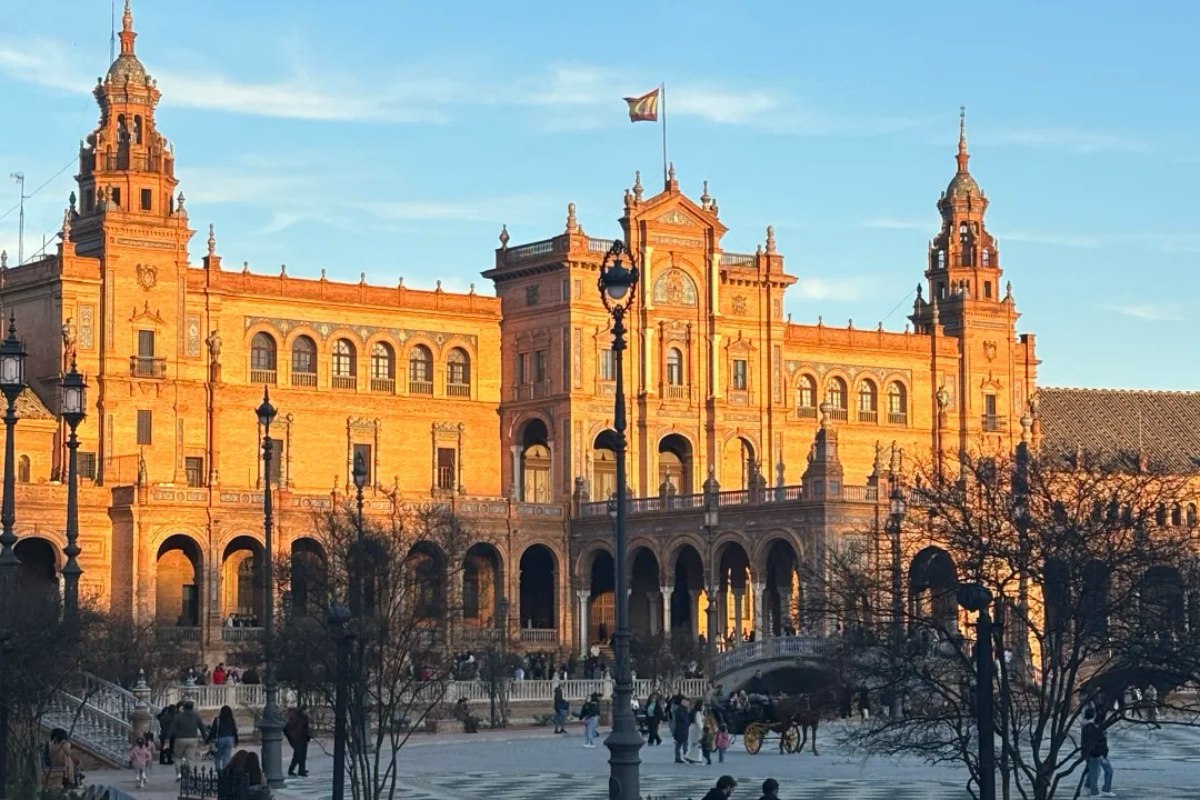 Golden sunset light illuminating Plaza de España in Seville during winter months with tourists enjoying mild weather and warm architecture