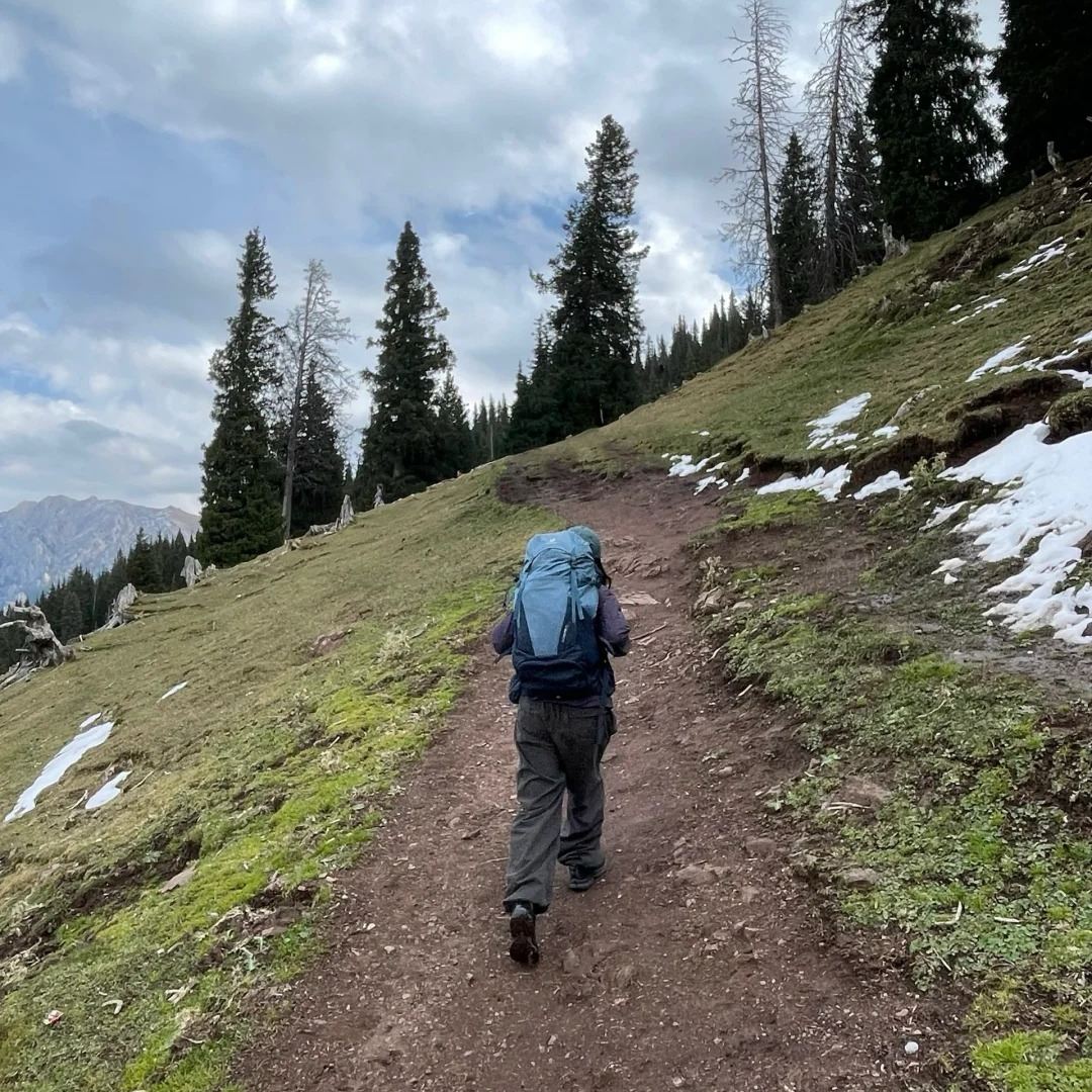 Minimalist travel packing hiker with compact backpack on mountain trail