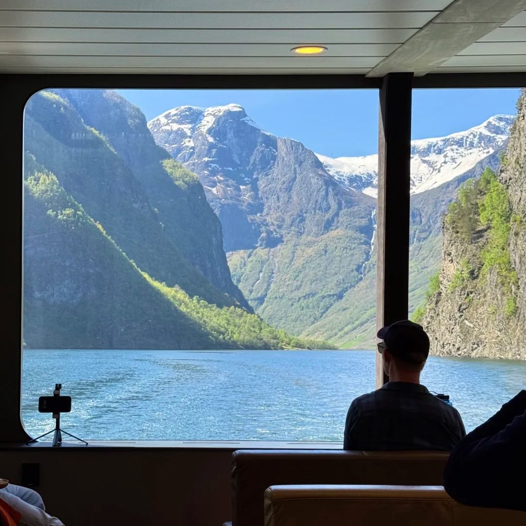 Norway travel ferry interior view showing passenger enjoying fjord scenery through large windows