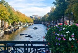 Places stay Amsterdam canal bridge decorated with colorful flowers and traditional Dutch bicycle